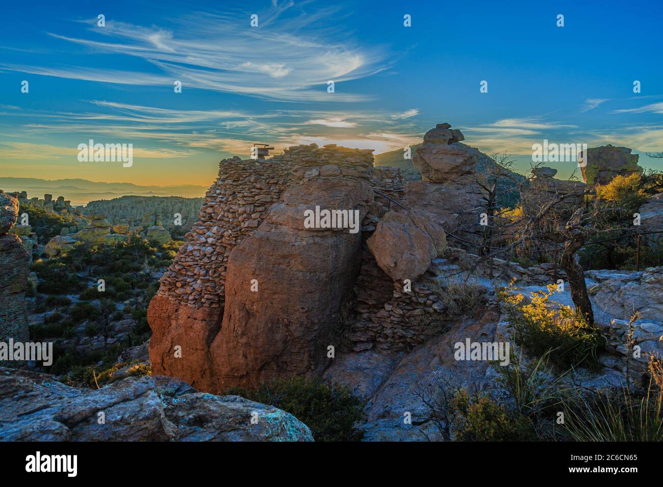 Golden light casts a glow on the formations of Chiricahua National Monument in southern Arizona. The observation tower was built by the Civilian Conse Stock Photo