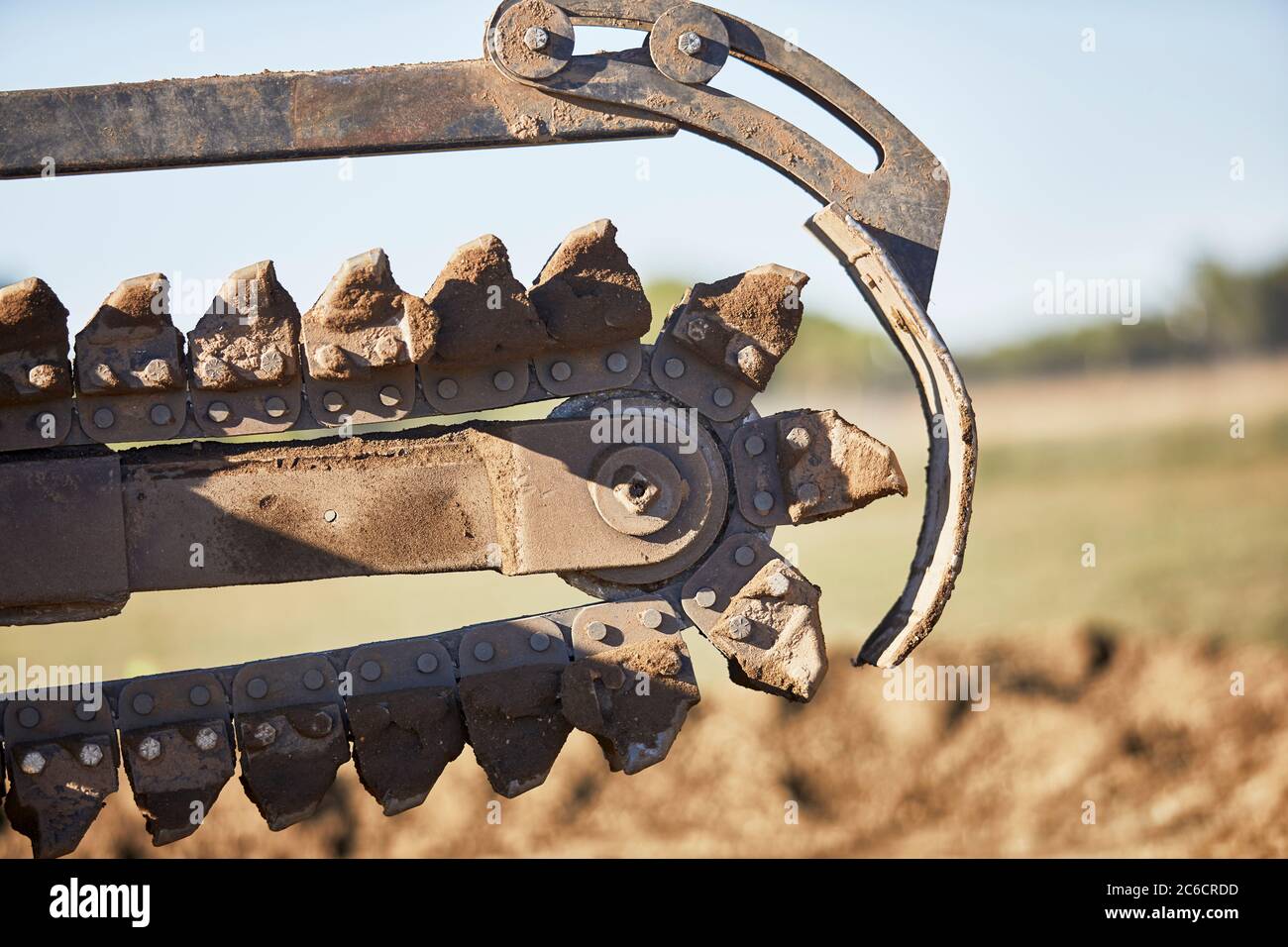 Close up of a Trencher chain in motion preparing to dig a trench in dirt Stock Photo