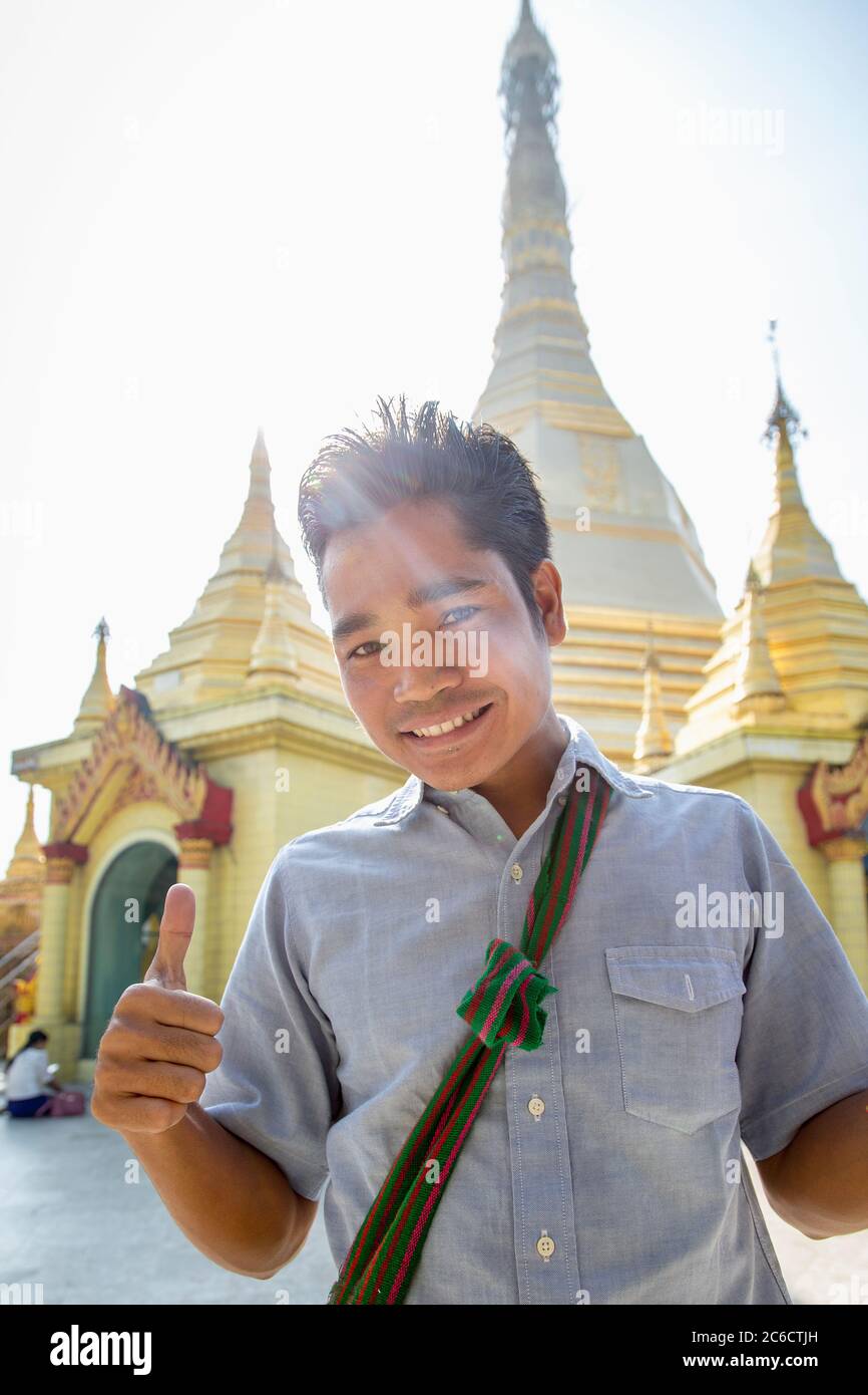 A tourist guide poses for a photo in front of a stupa at the Shwedagn Pagoda in Yangon, Myanmar Stock Photo