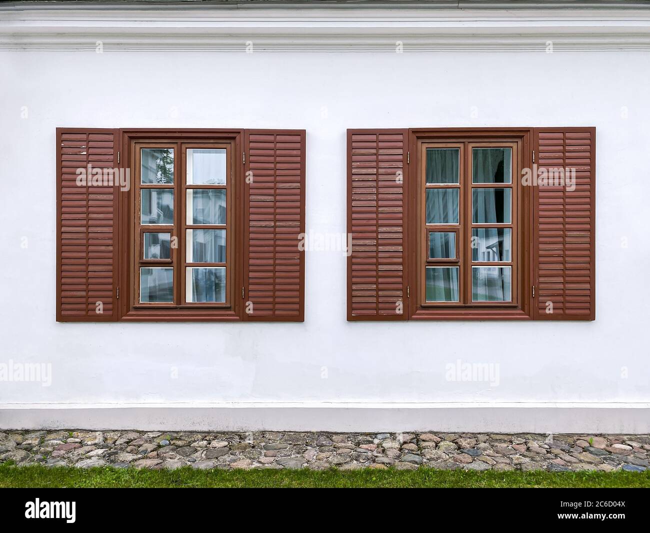 two traditional windows with open wooden shutters on the old building's stucco wall Stock Photo