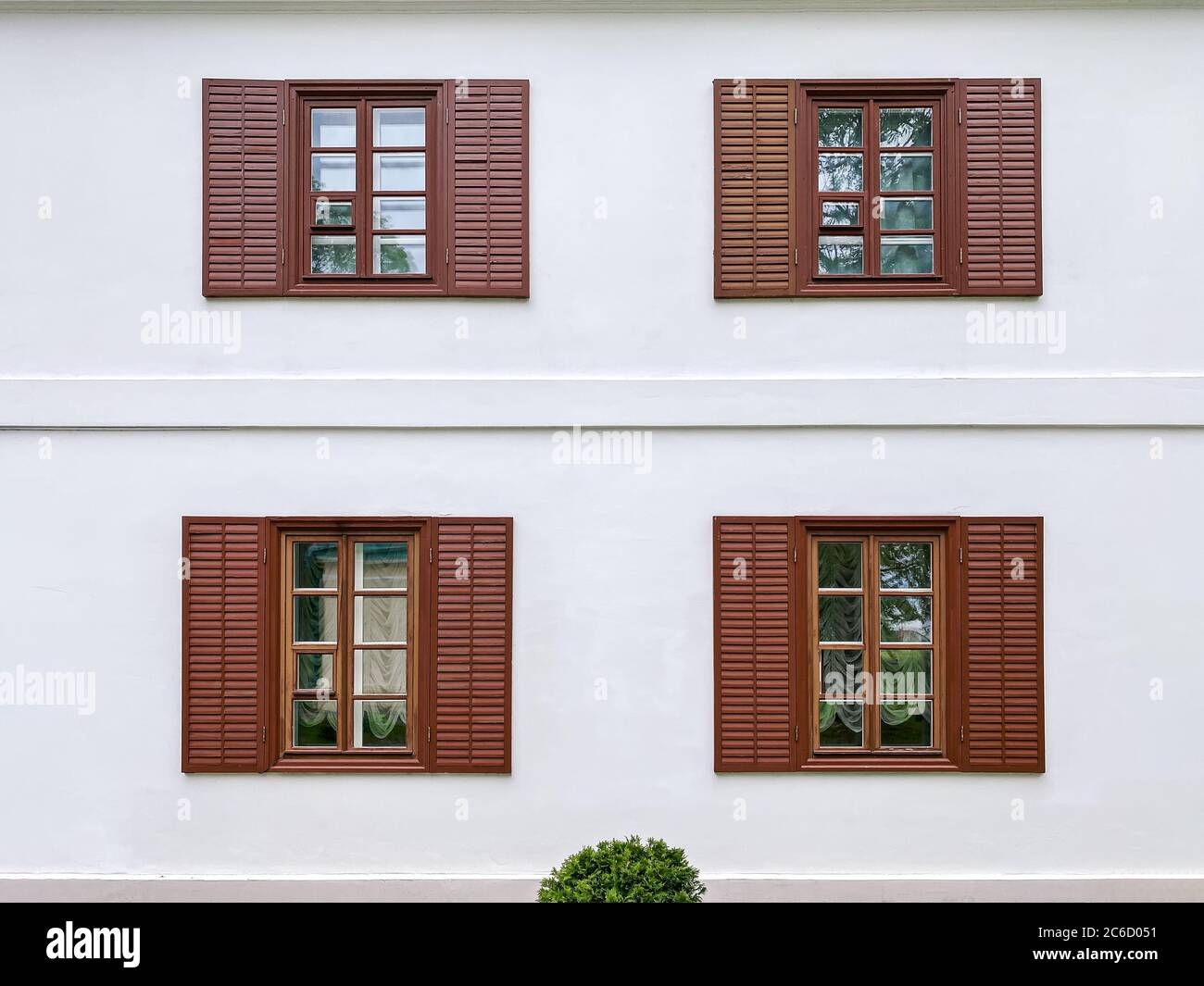 white exterior plaster wall with painted brown windows and wooden shutters Stock Photo