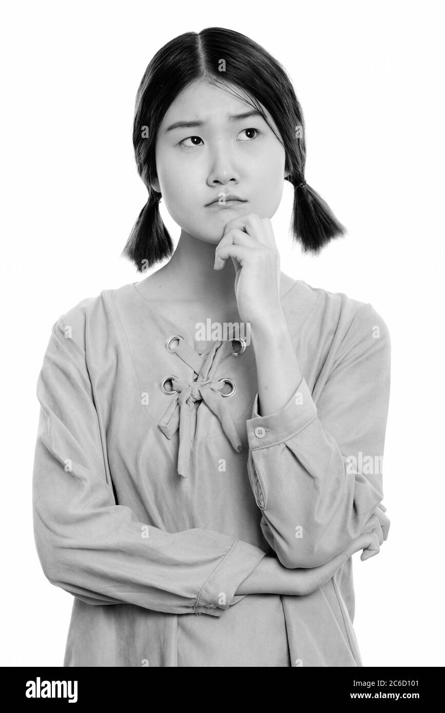 Studio shot of young beautiful Asian woman thinking while looking up ...