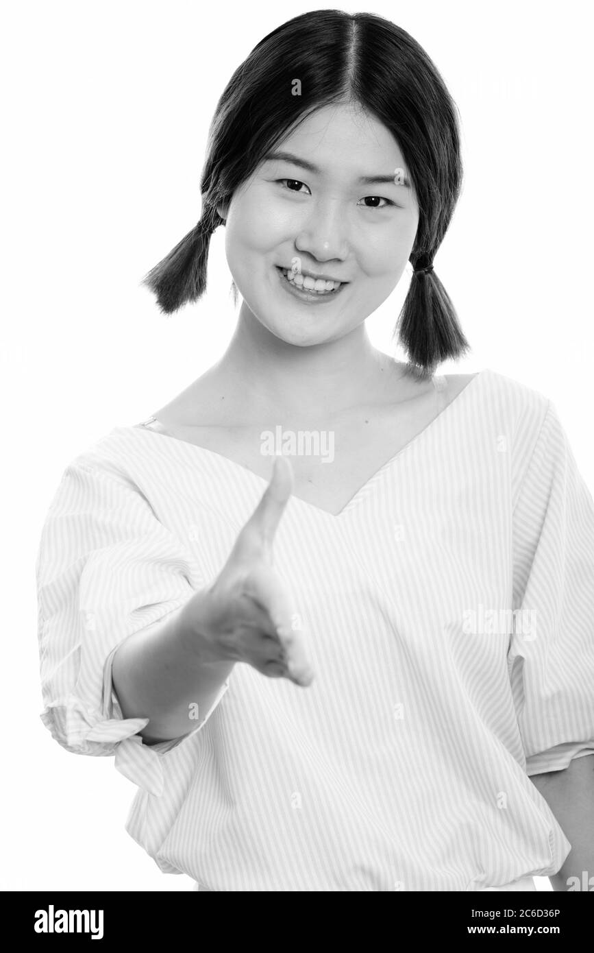 Studio shot of young happy Asian woman smiling while giving handshake ...
