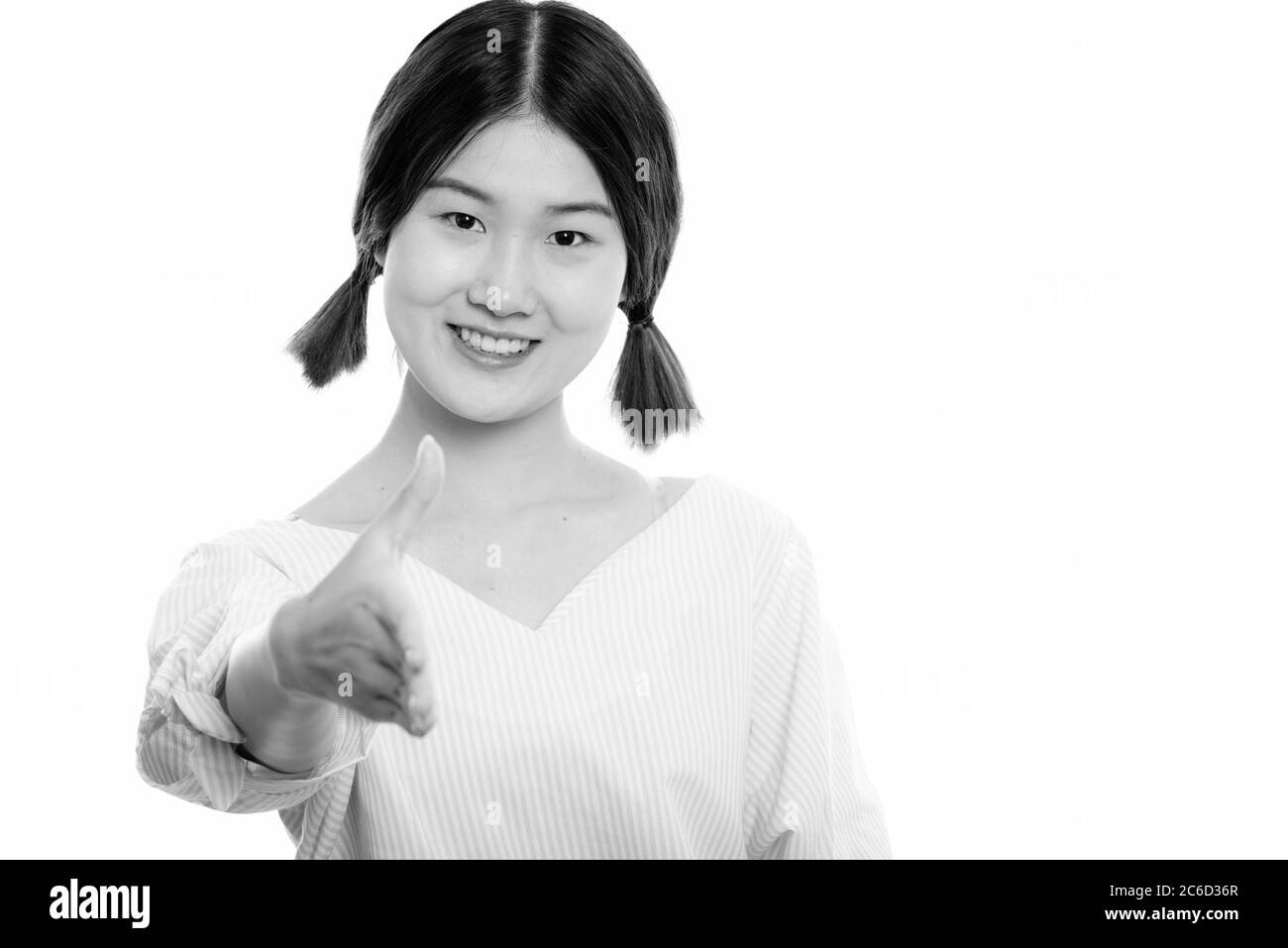 Studio shot of young happy Asian woman smiling while giving handshake ...