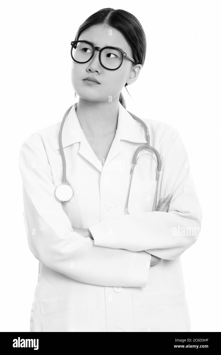 Studio shot of young beautiful Asian woman doctor thinking with arms ...