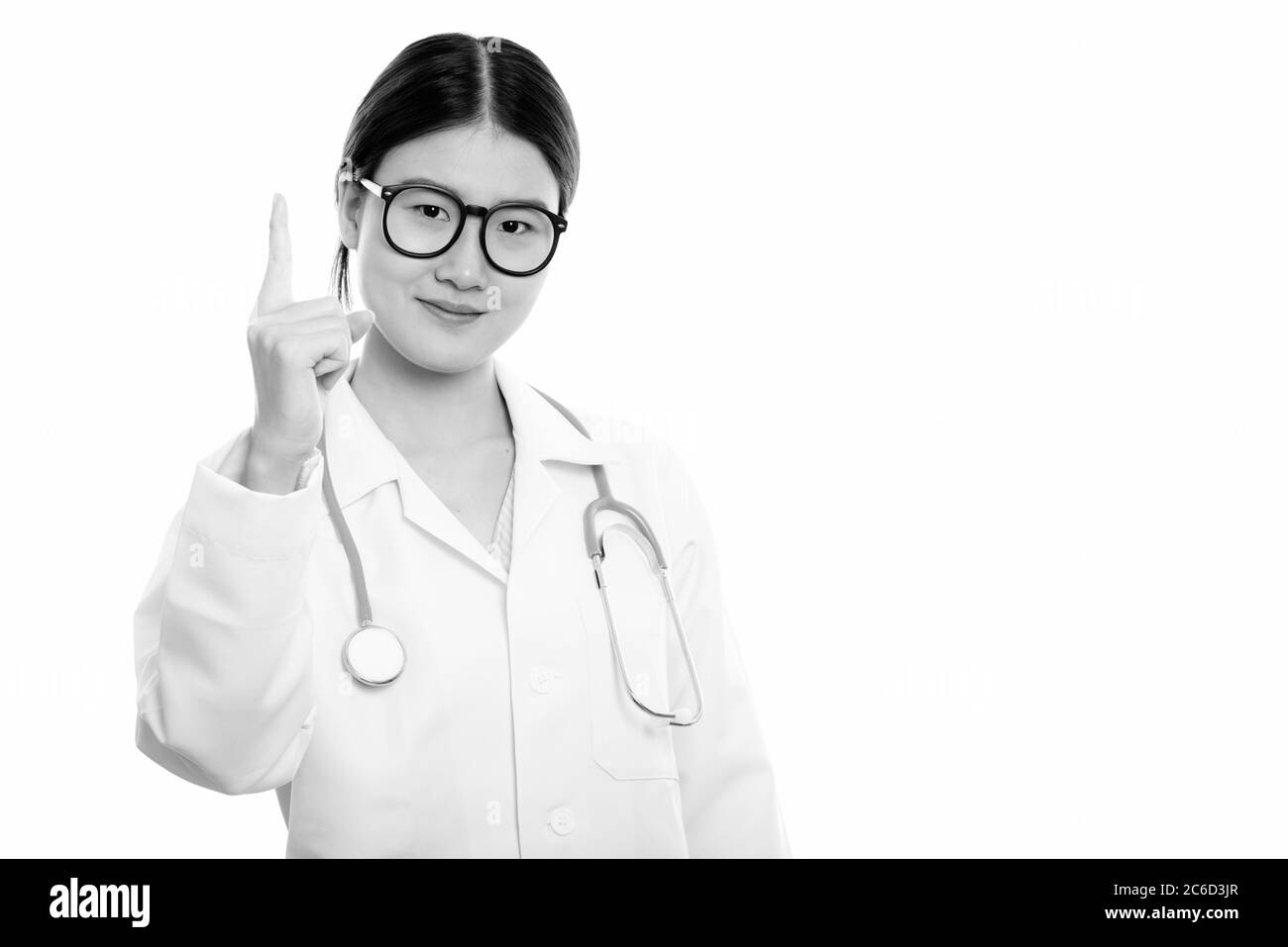 Studio shot of young beautiful Asian woman doctor pointing finger up ...