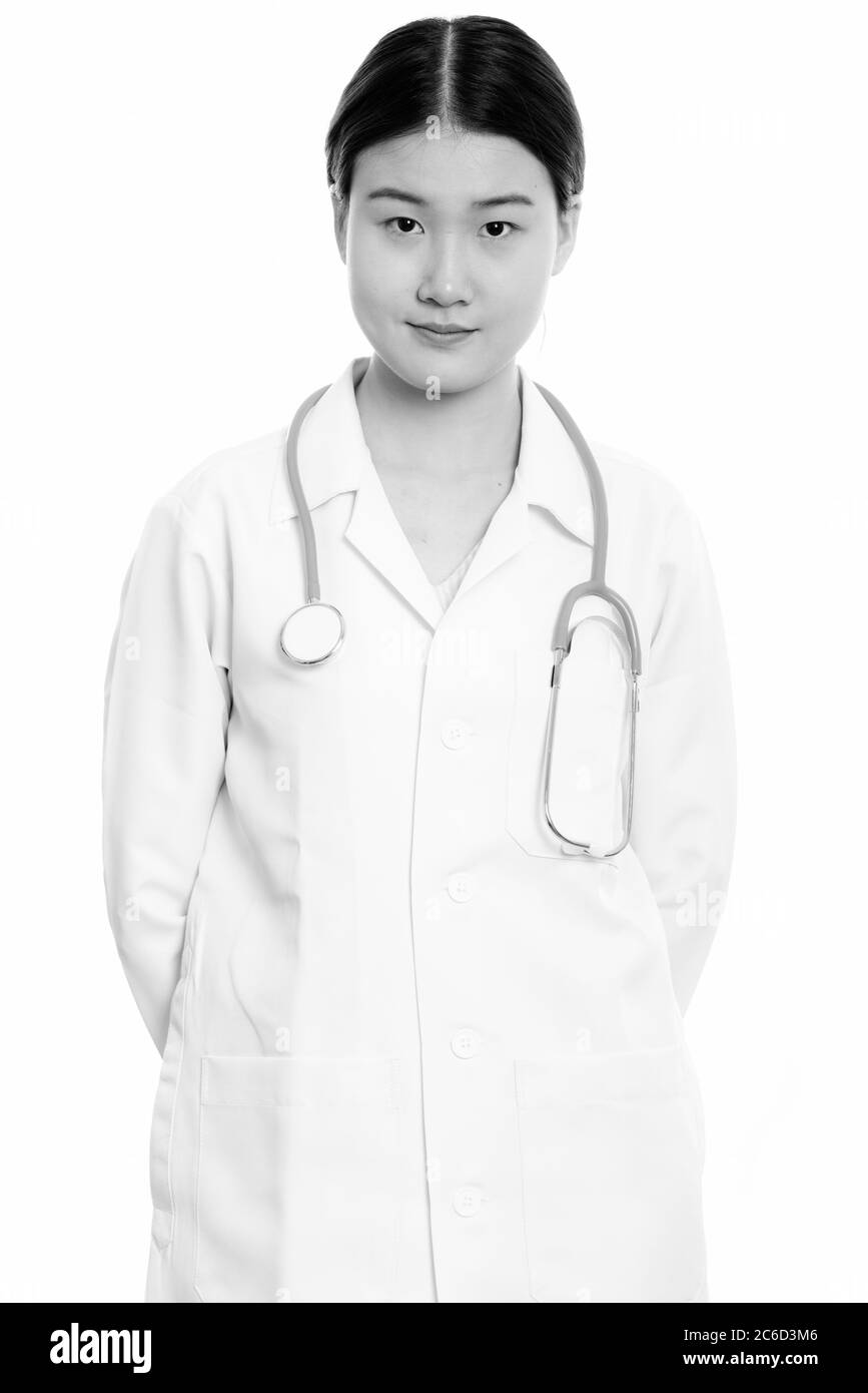 Studio shot of young beautiful Asian woman doctor with hands on back ...