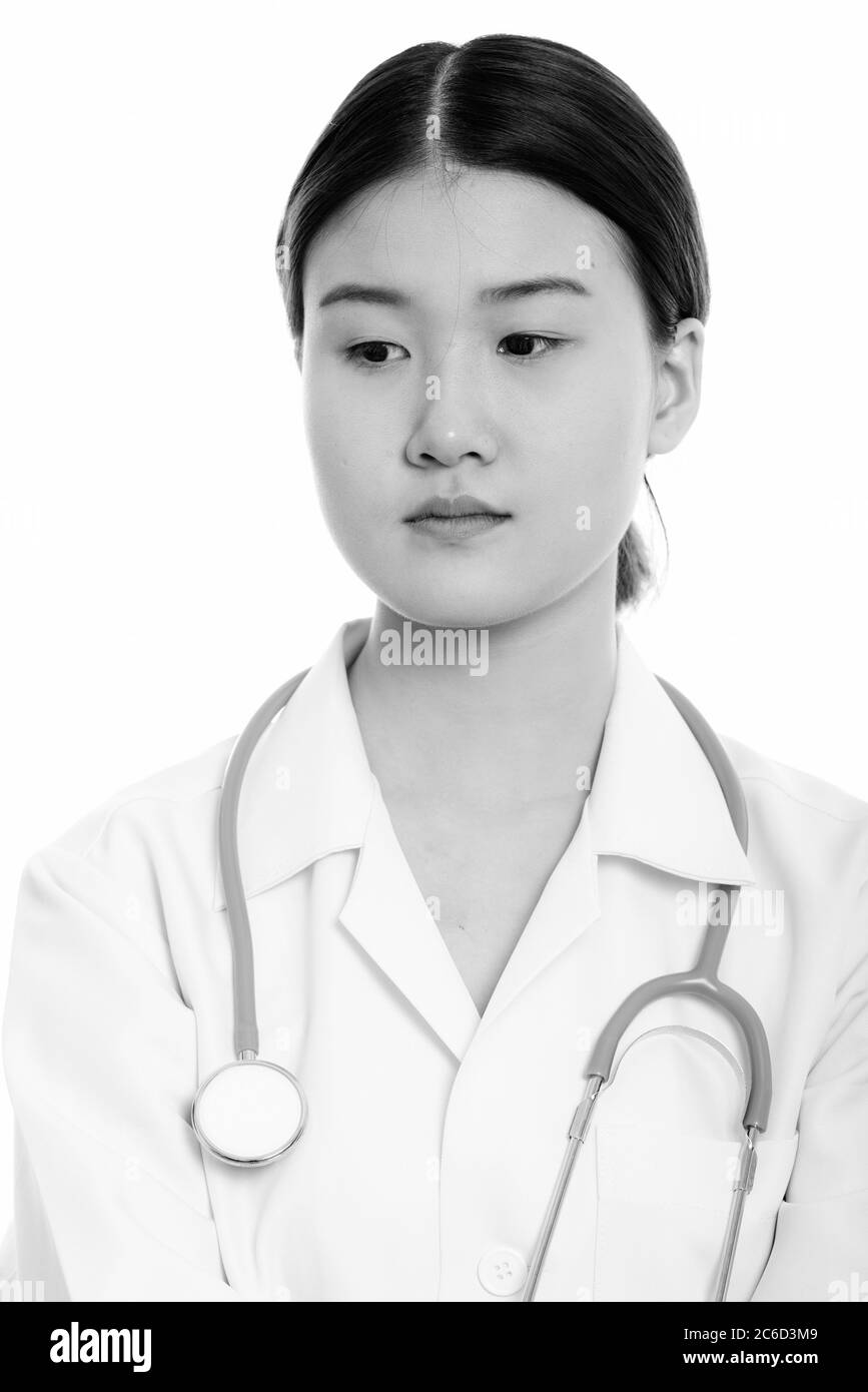Studio shot of young beautiful Asian woman doctor thinking while ...