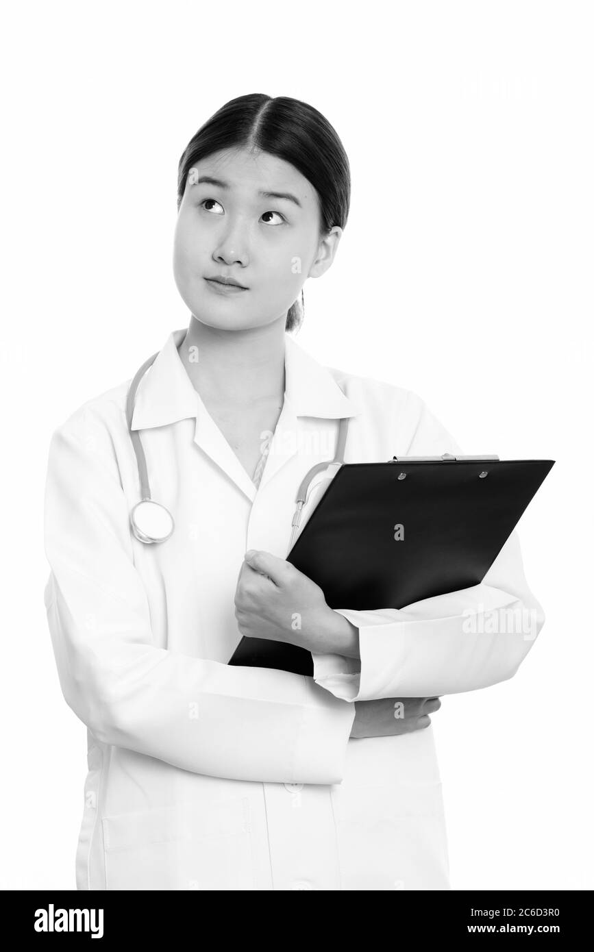 Studio shot of young beautiful Asian woman doctor holding clipboard ...