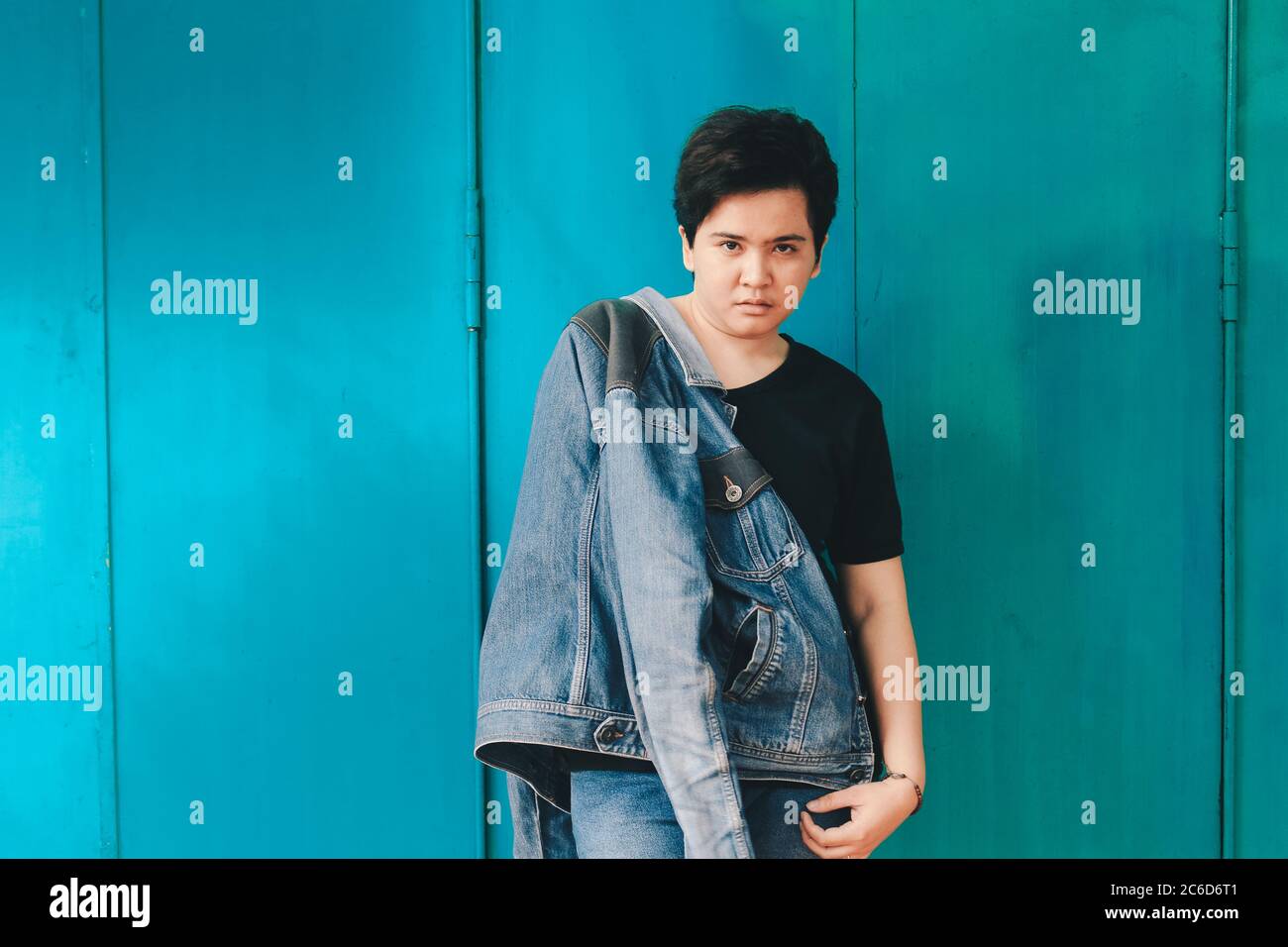 Asian beautiful short hair girl holding jeans jacket on blue background  with sharp looking expression Stock Photo - Alamy