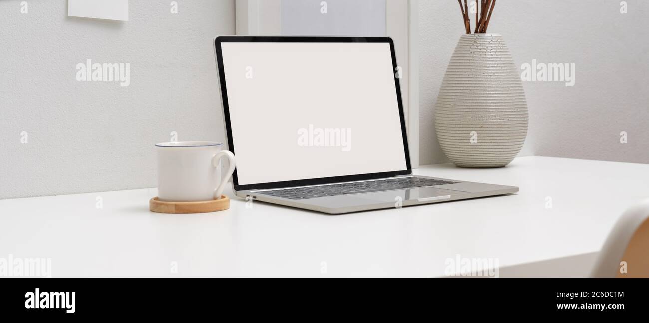 Side view of minimal worktable with mock-up laptop, books, coffee cup ...