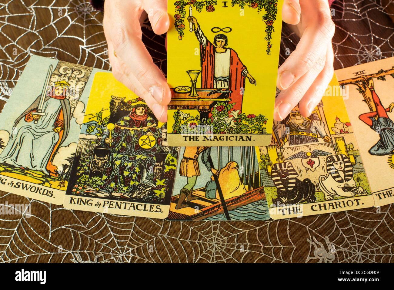 Tarot cards from the 1910 Rider-Waite design. Tarot reading with cards and crystal and The Magician card held up. Spider web background. Stock Photo