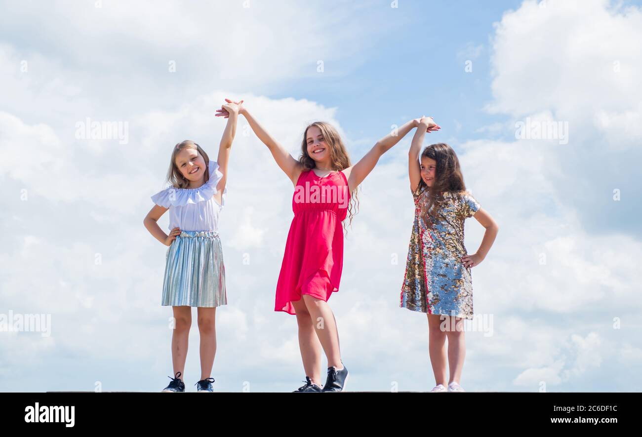 we are strong. sisterhood and friendship. family bonding time. best friends forever. three sisters on sky background. happy childhood. summer vacation. small girls hold hands. love and support. Stock Photo