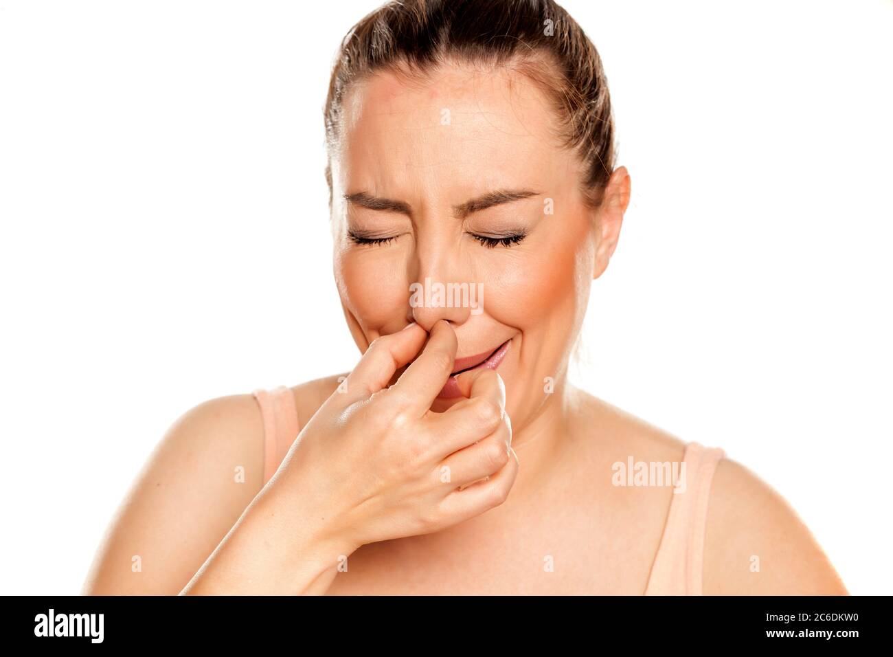 A young woman has itching in the nose on white background Stock Photo