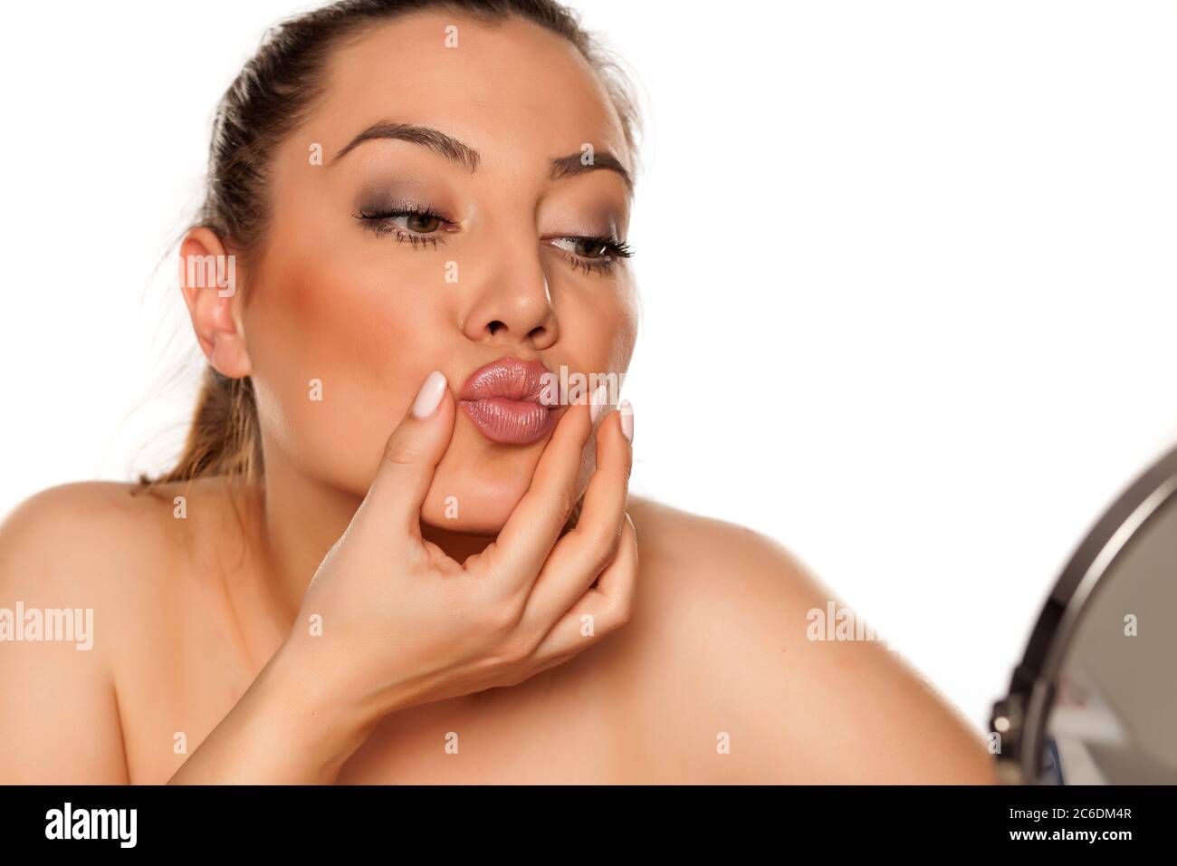 Portrait of beautiful woman checking her lips on white background Stock Photo