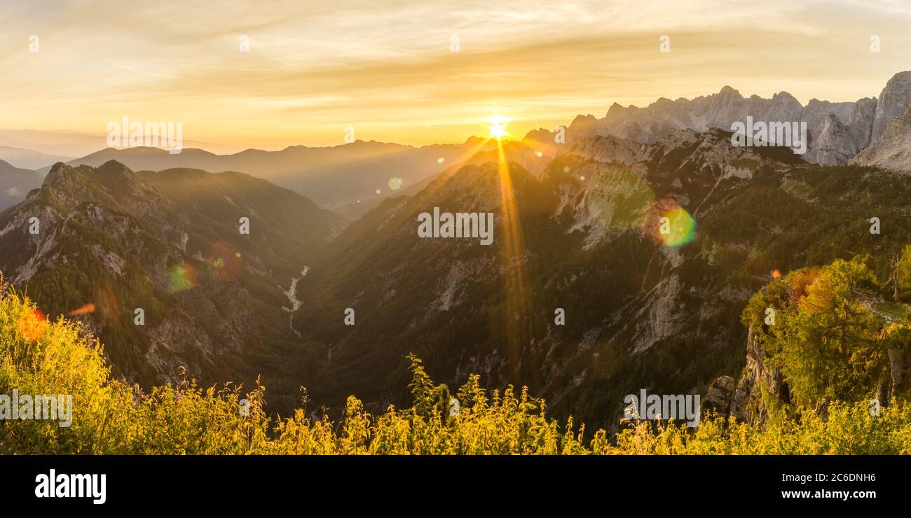 Amazing sunrise in the mountains. Backlight Sunlight with beautiful lens flares and sunbeams. Panorama Julian Alps, Triglav National Park, Slovenia Stock Photo