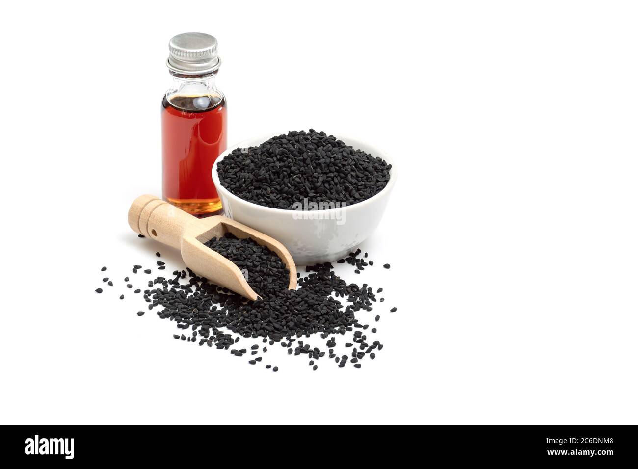 Black cumin seeds in bowl and essential oil in glass bottle. Nigella sativa isolated on white background. Stock Photo