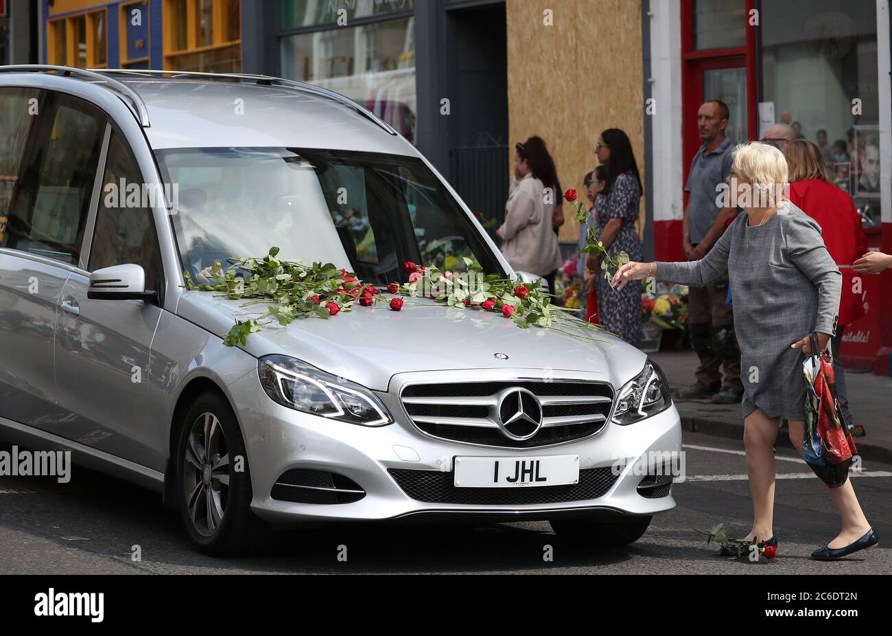 People place flowers on the funeral cortege of xander irvine hires