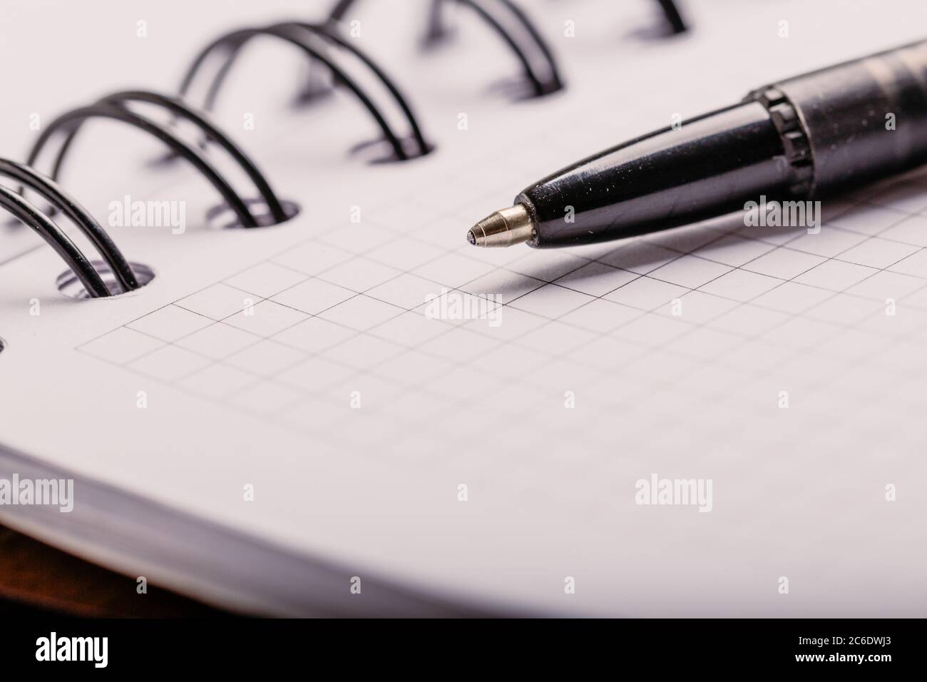Opened notepad in a cage with an automatic plastic ballpoint pen close-up. Stock Photo