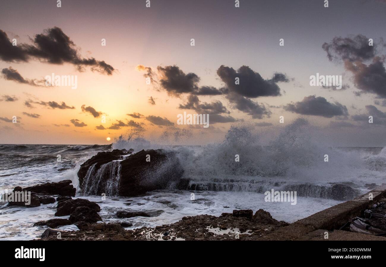 The ancient port of Caesarea, Israel at Sunset. Waves are breaking on the breakwater Stock Photo