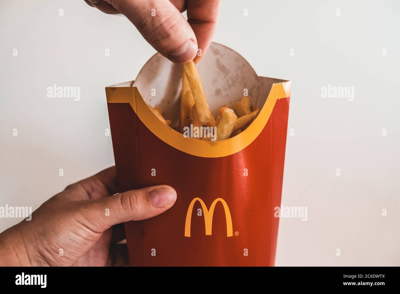 Lviv / Ukraine - April 2020: Close up view of hungry man's hand taking a piece of french fries from Mcdonalds bag. Ordering unhealthy takeaway food Stock Photo