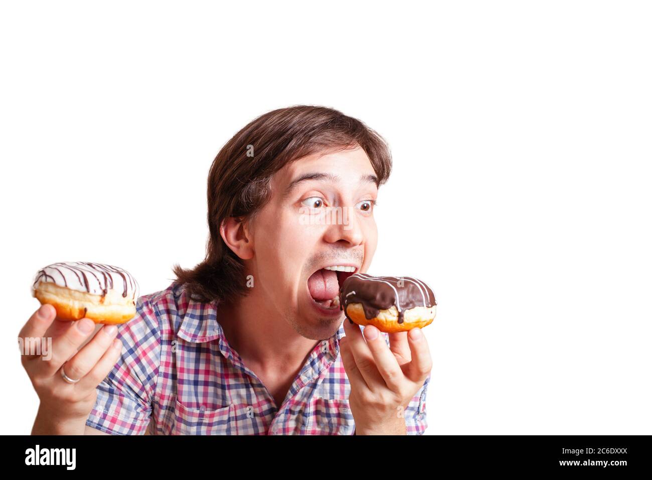Funny man looks at the chocolate doughnut bulging eyes, a very funny photo on a white background. Empty space for text. A man loves sweets chocolate. Stock Photo
