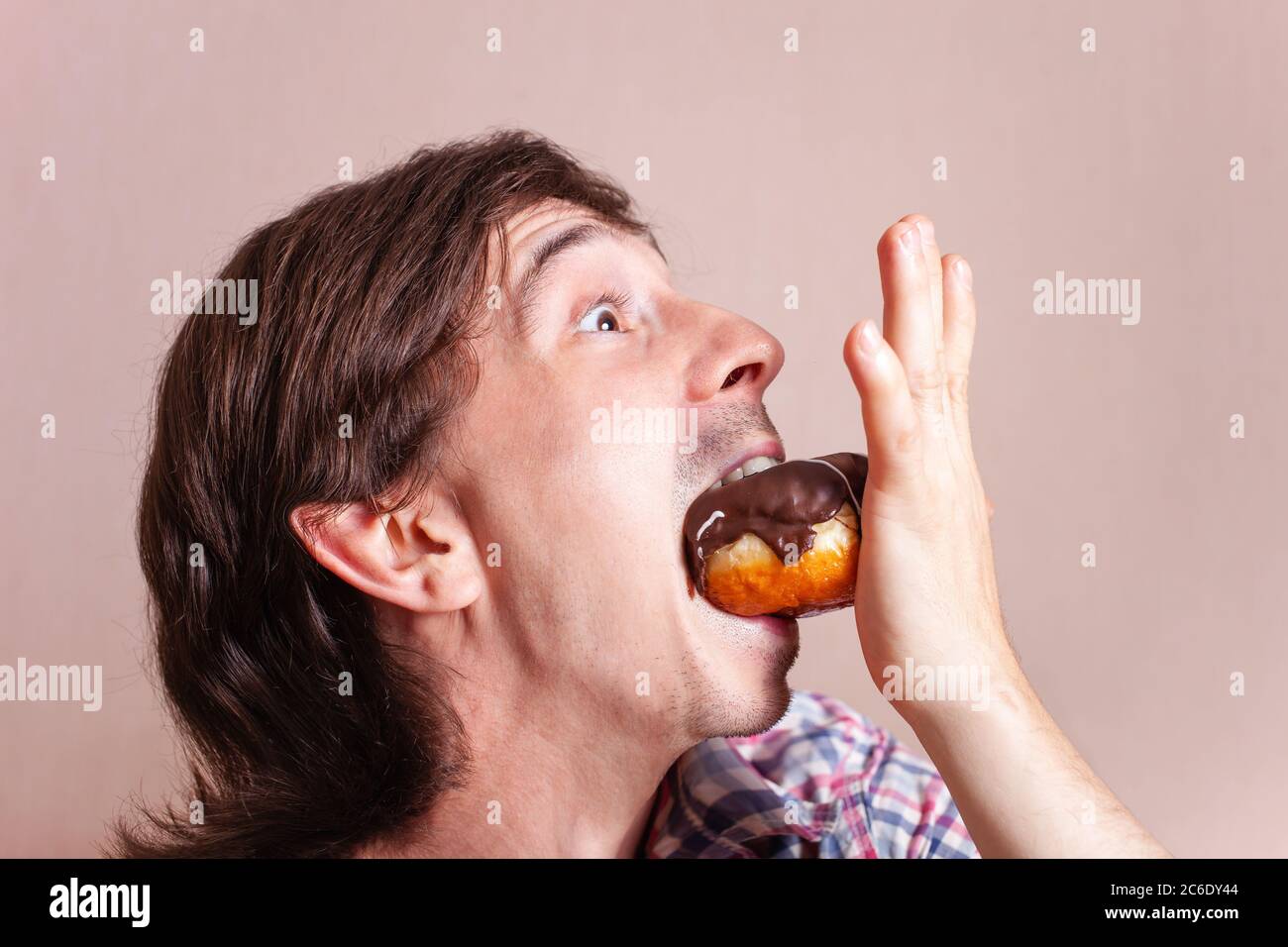 Elf shoves a sweet doughnut, a man loves a sweet, male portrait on a pink background, a very funny photo. Stock Photo