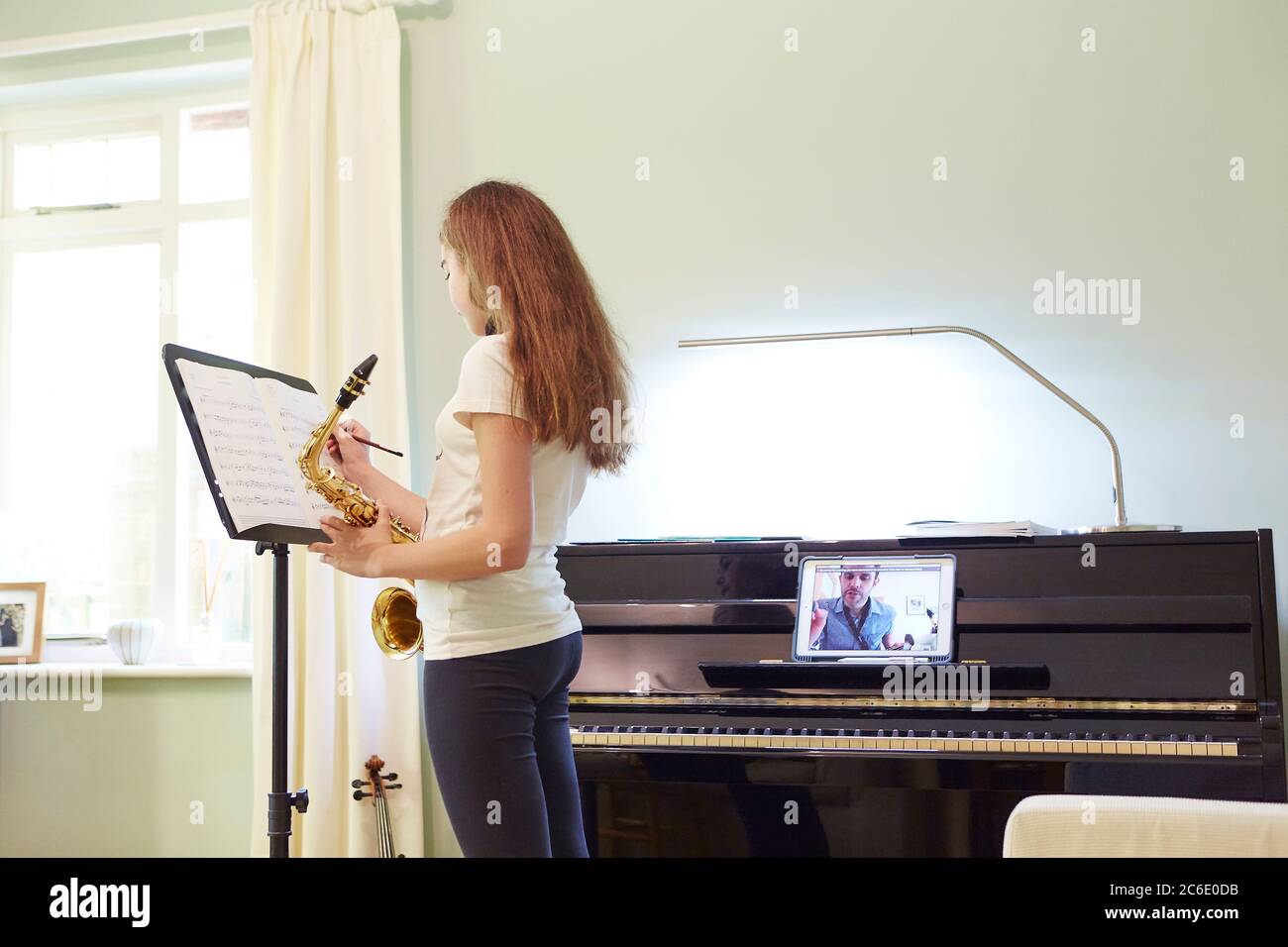 Girl taking online saxophone lesson at home Stock Photo