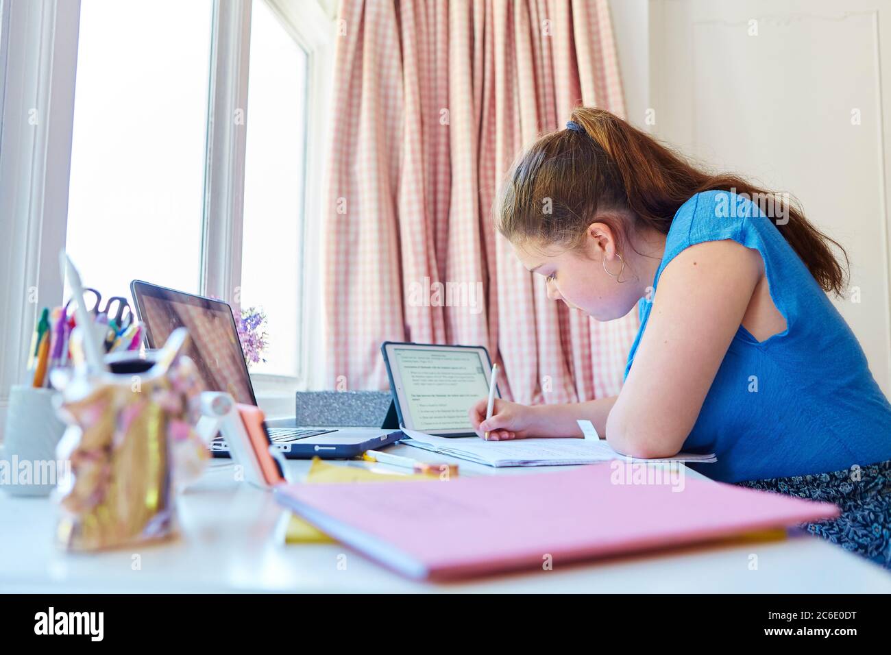 Girl homeschooling at desk in bedroom Stock Photo