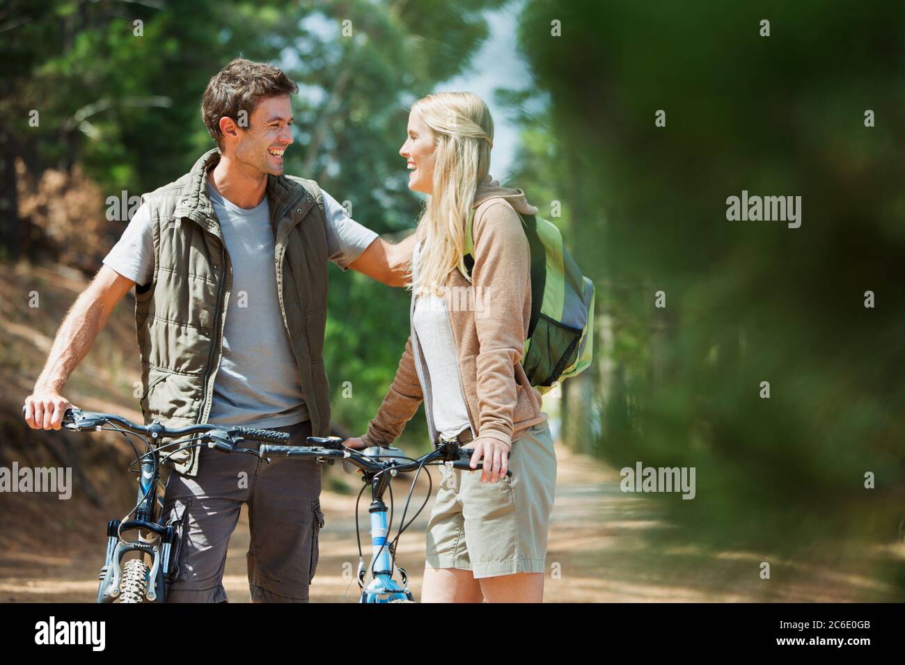 Smiling couple with mountain bikes in woods Stock Photo