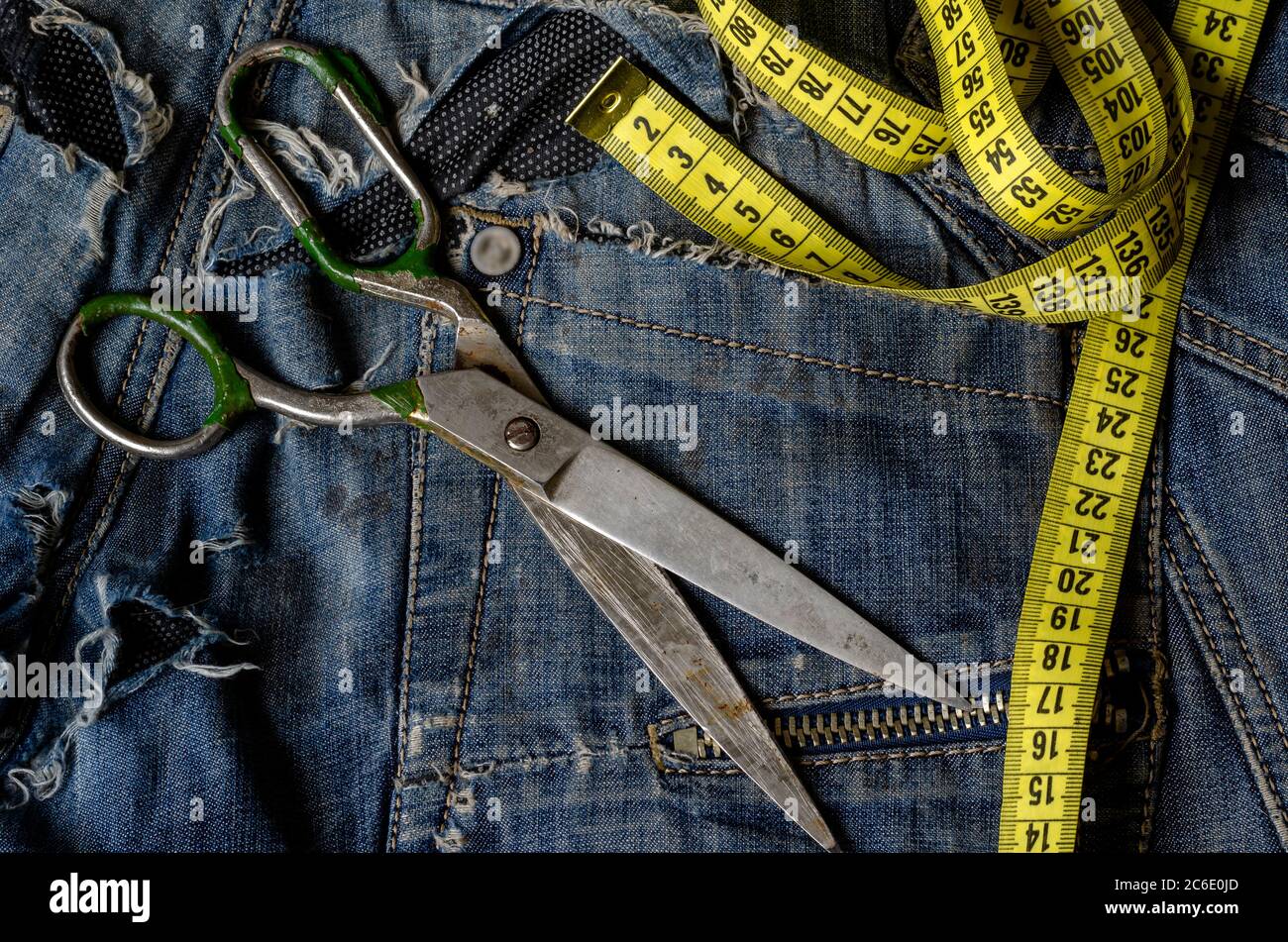 https://c8.alamy.com/comp/2C6E0JD/tailoring-and-design-concept-metal-scissors-ruler-and-yellow-measure-tape-in-denim-pants-pockets-2C6E0JD.jpg