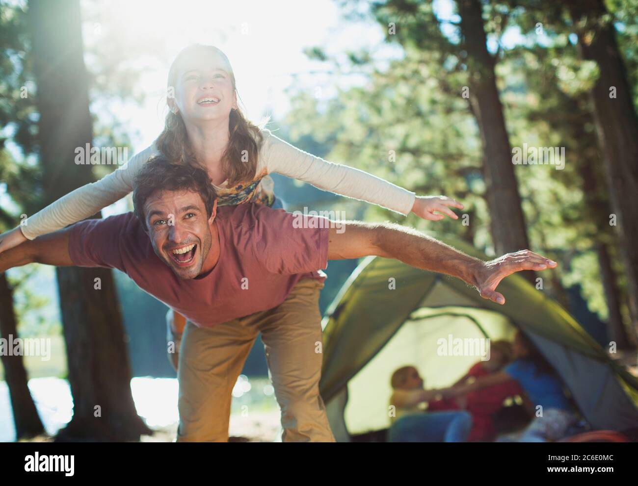 Exuberant father carrying daughter on back in woods Stock Photo