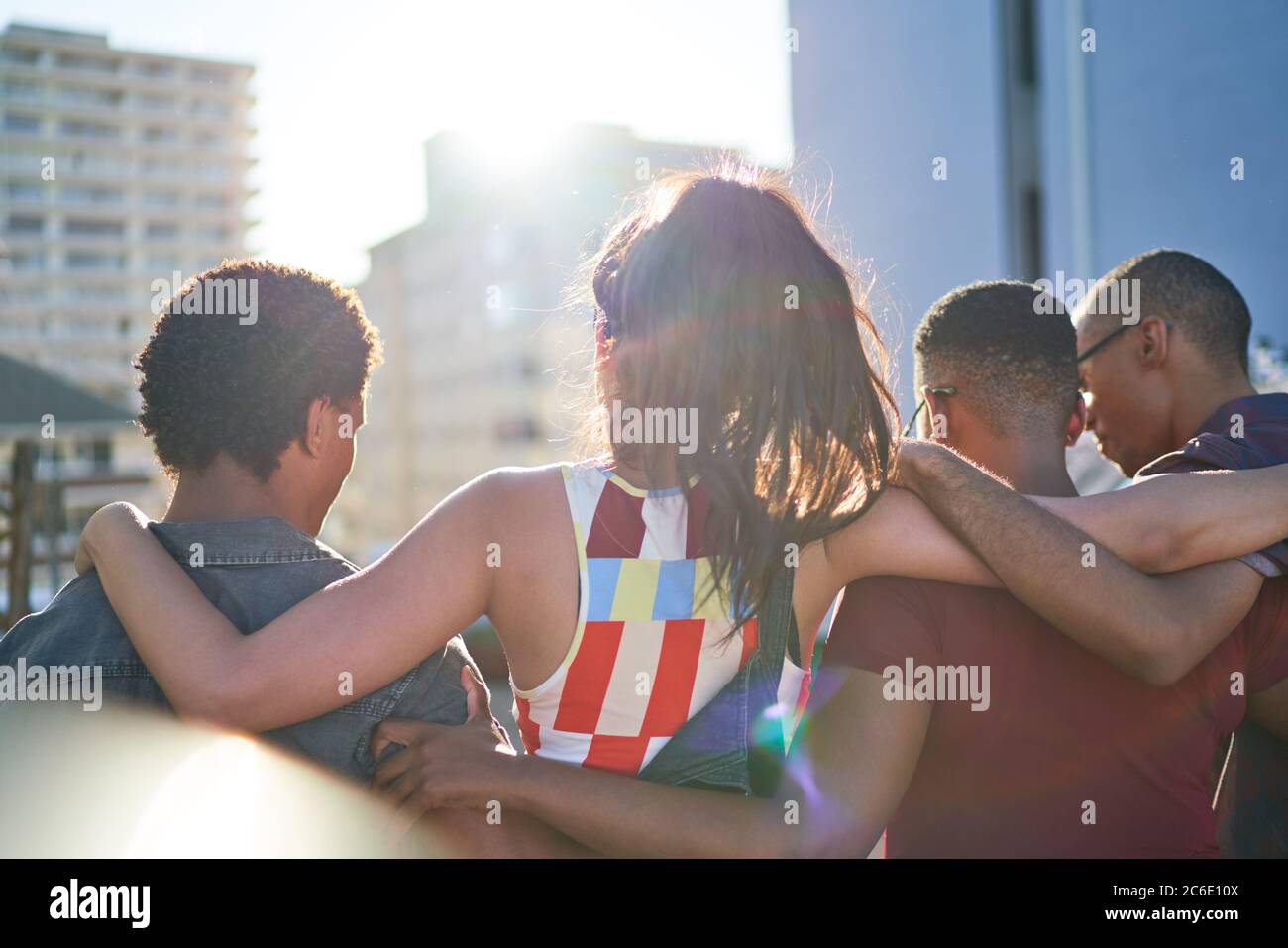 Young friends hugging and hanging out on sunny rooftop balcony Stock Photo