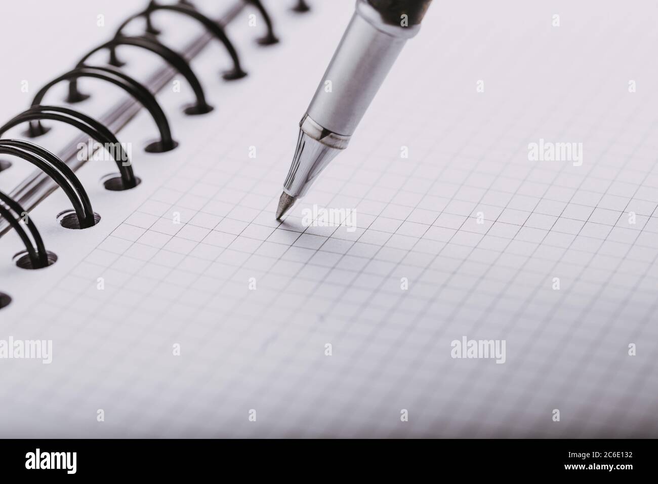 Opened notepad in a cage with an automatic plastic ballpoint pen close-up. Stock Photo