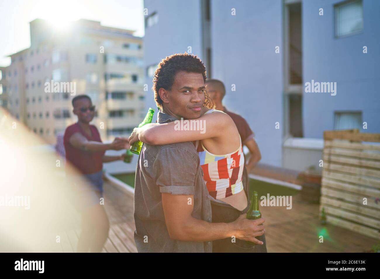 Portrait young couple hugging and drinking beer on urban rooftop Stock Photo