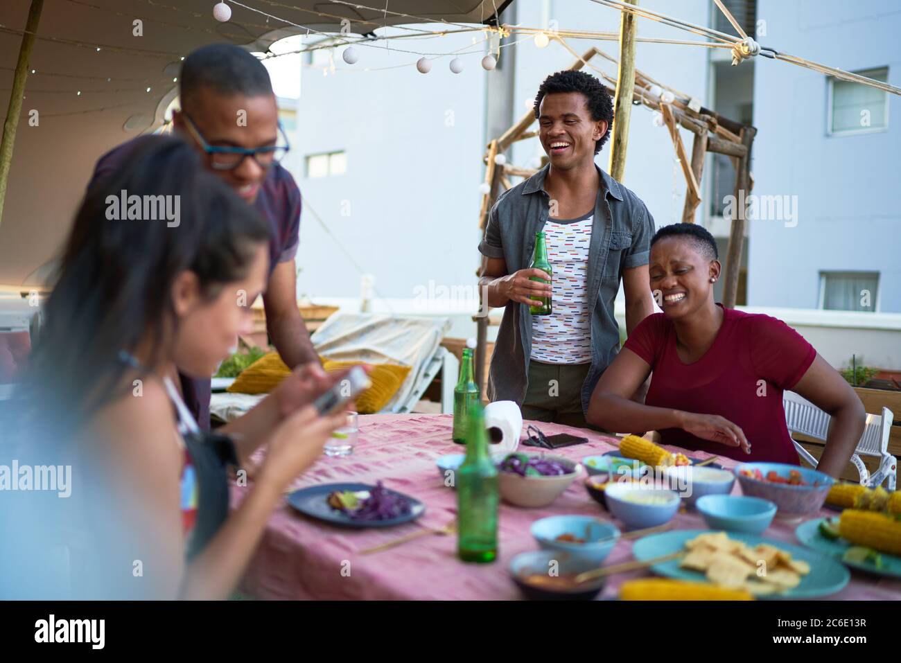 Happy young friends enjoying dinner on rooftop balcony Stock Photo