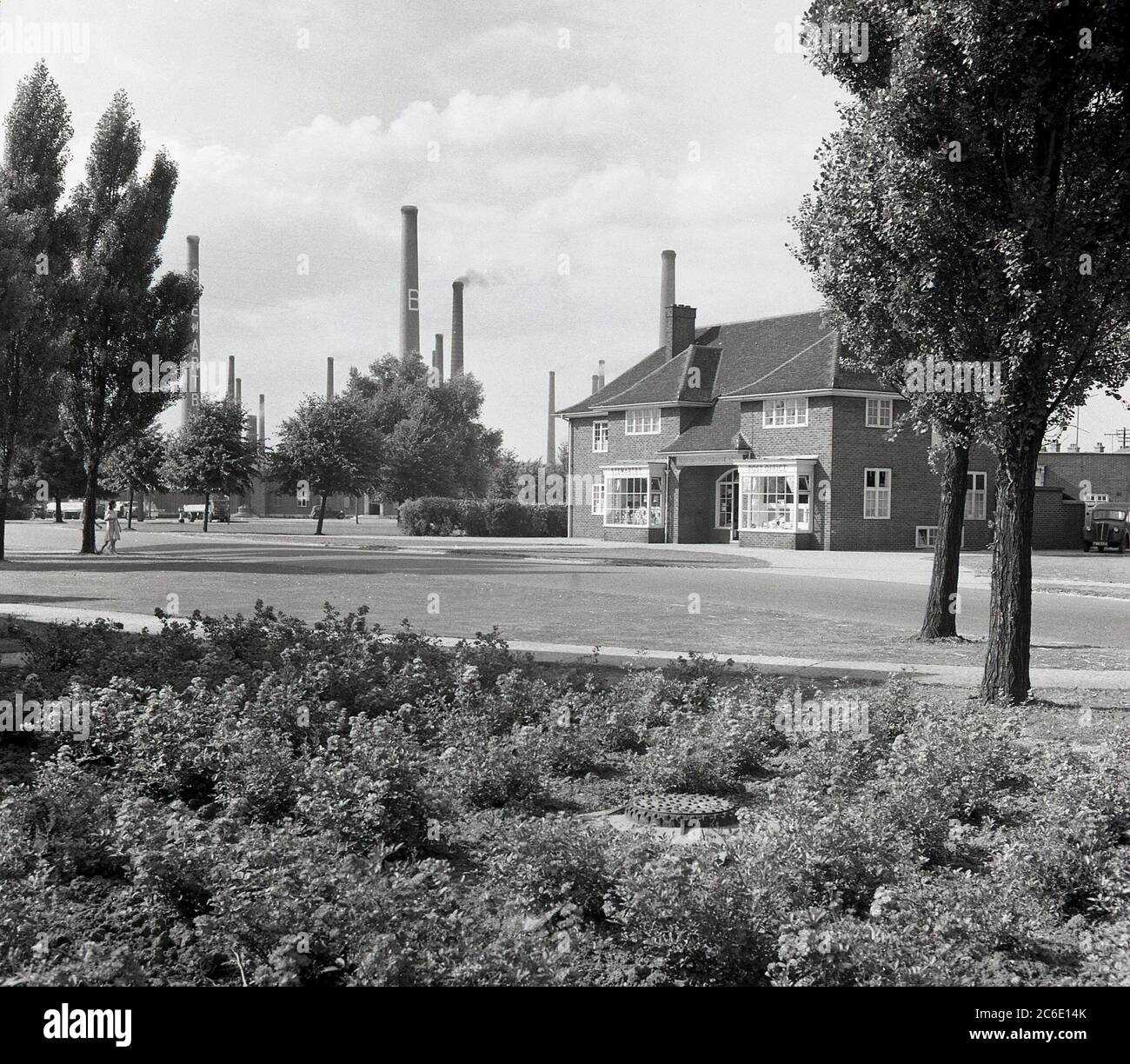 1950s, historical picture showing the 'Co-Operative' store and Post Office at the model village of Stewartby, Bedfordshire, the site of the London Brick Company, at the time, the largest brickworks in the world.  Several of the giant industral chimneys from the brickfiring kilns can be seen in the background. The Stewart family, owners of London Bricks were paternal employers and provided their large workforce with housing and sports and leisure facilities, carrying on a tradition started by the Quaker families of the previous century. Stock Photo