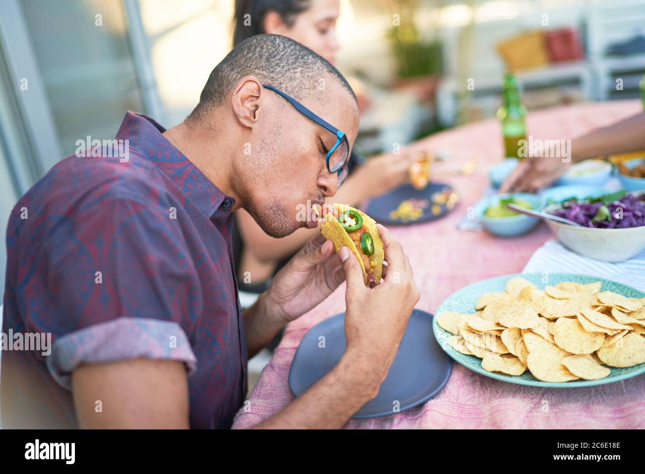 Young man eating taco at patio table Stock Photo