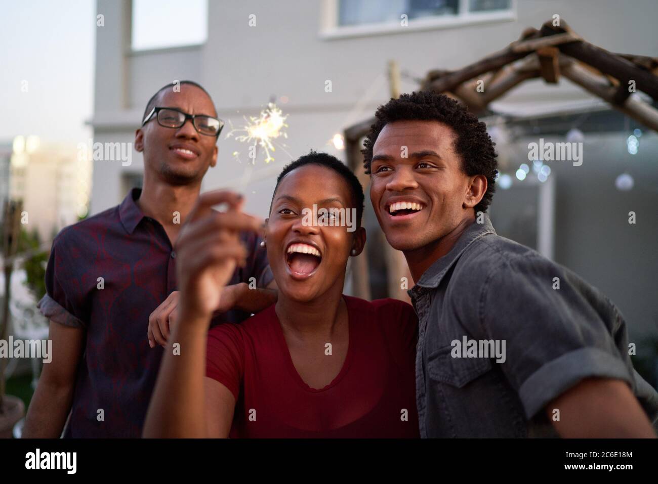 Happy young friends with sparkler on patio Stock Photo