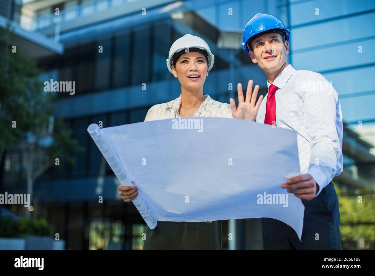 Architects reviewing blueprints outside urban building Stock Photo