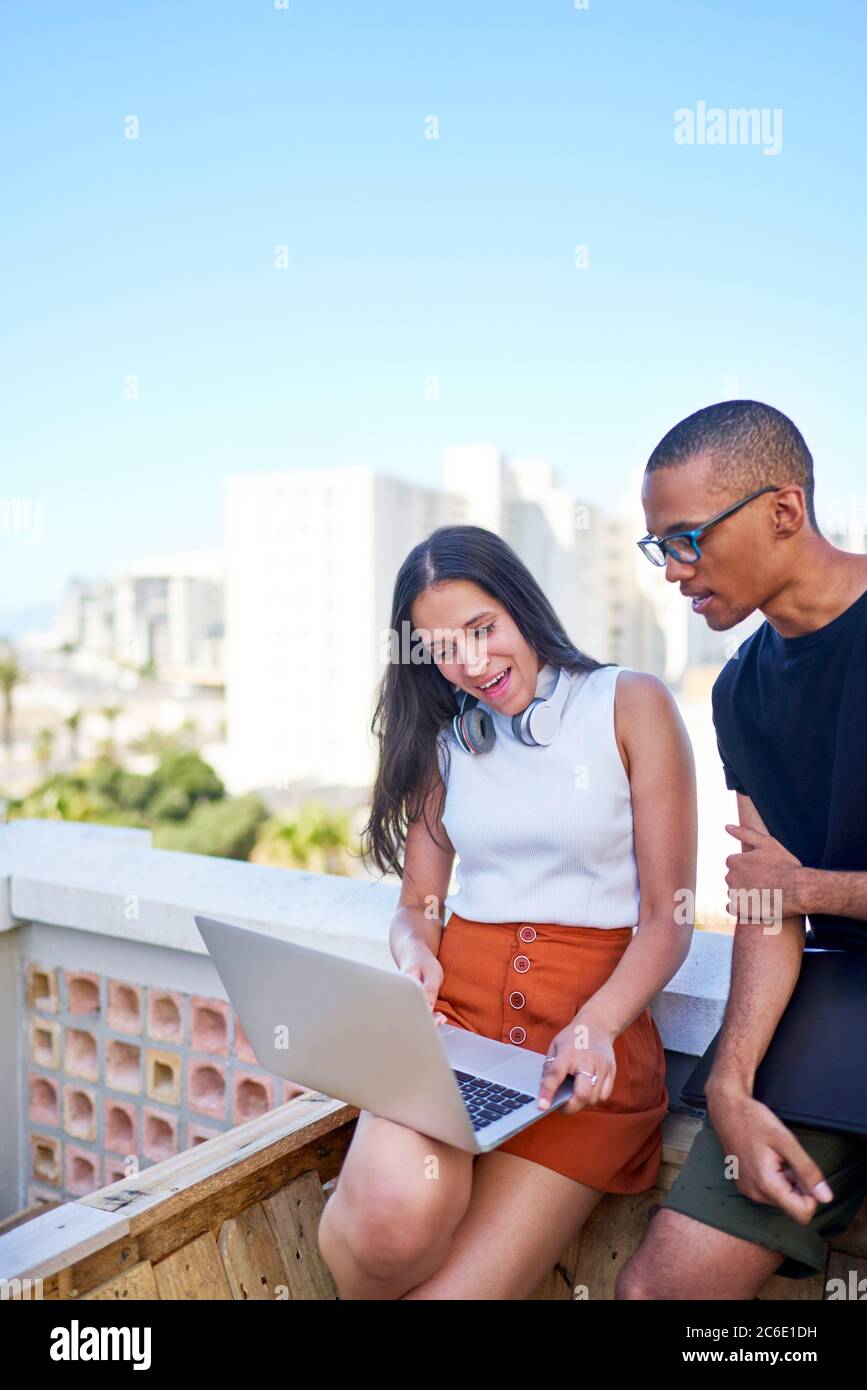 Young business people with laptop working on urban rooftop Stock Photo