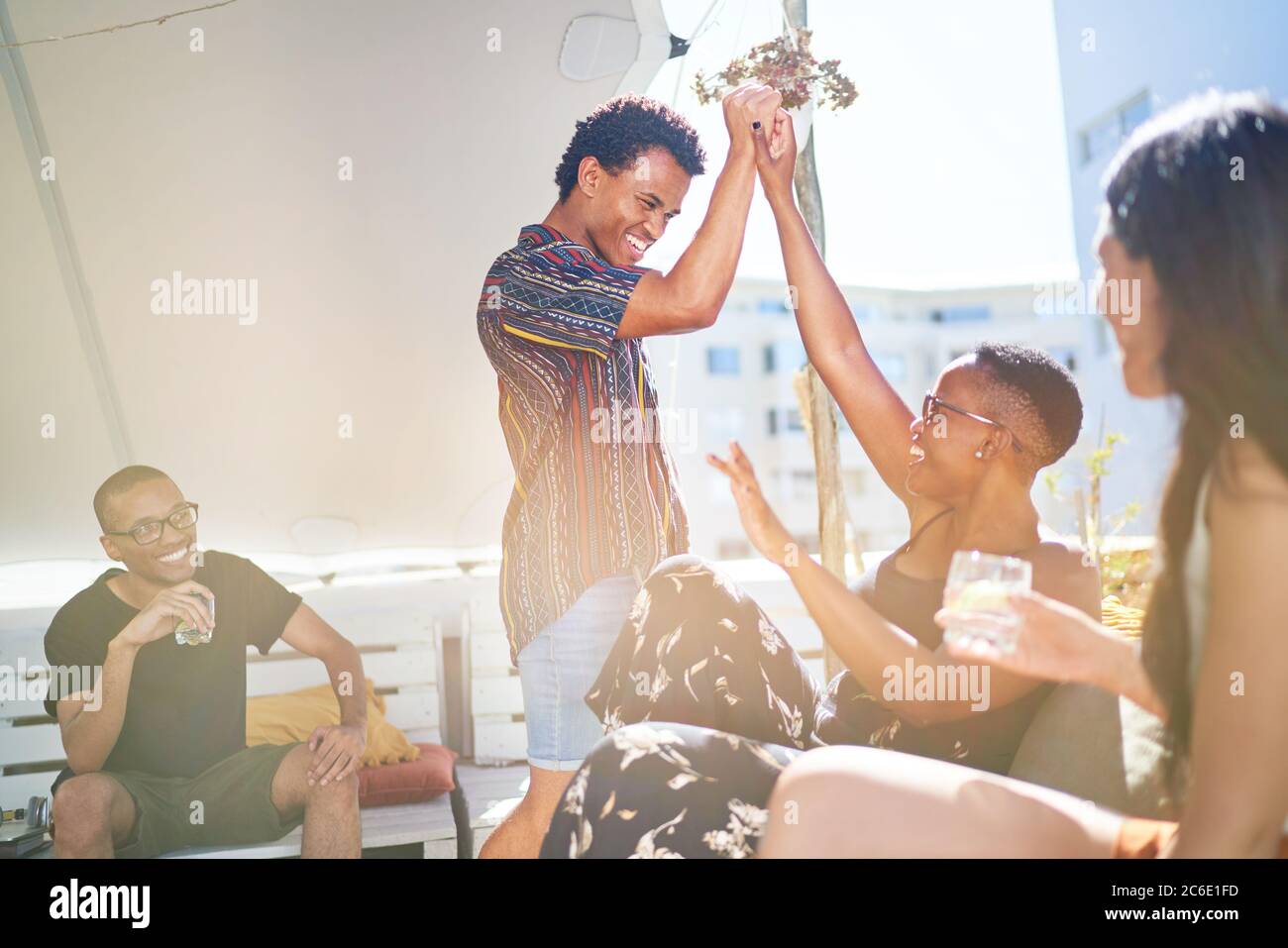 Happy young friends high fiving on sunny rooftop balcony Stock Photo