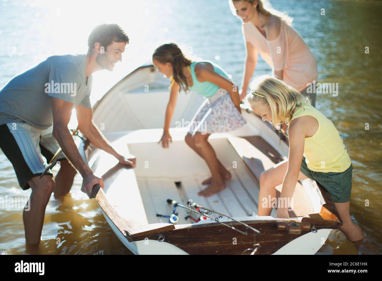Family getting into rowboat with fishing rods on lake Stock Photo