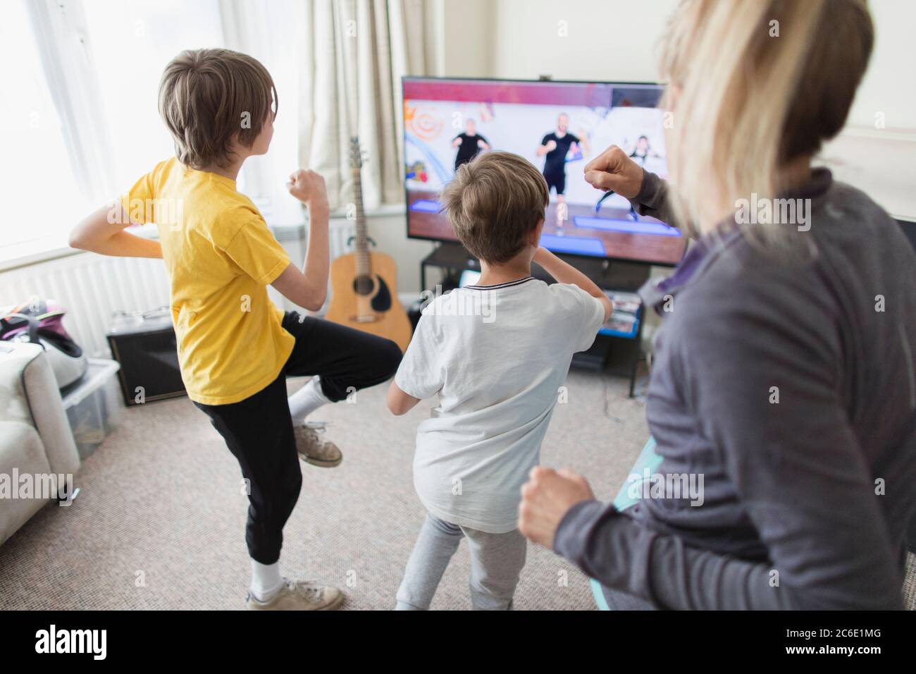 Family exercising at TV in living room Stock Photo