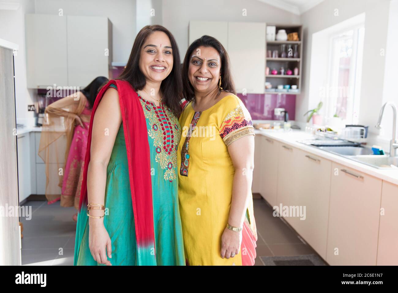 Portrait happy Indian sisters in traditional saris in kitchen Stock Photo