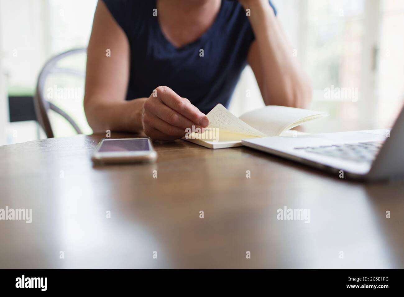 Woman with notebook working from home at laptop Stock Photo