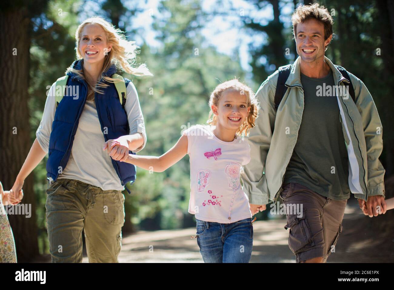 Smiling family holding hands and running in woods Stock Photo