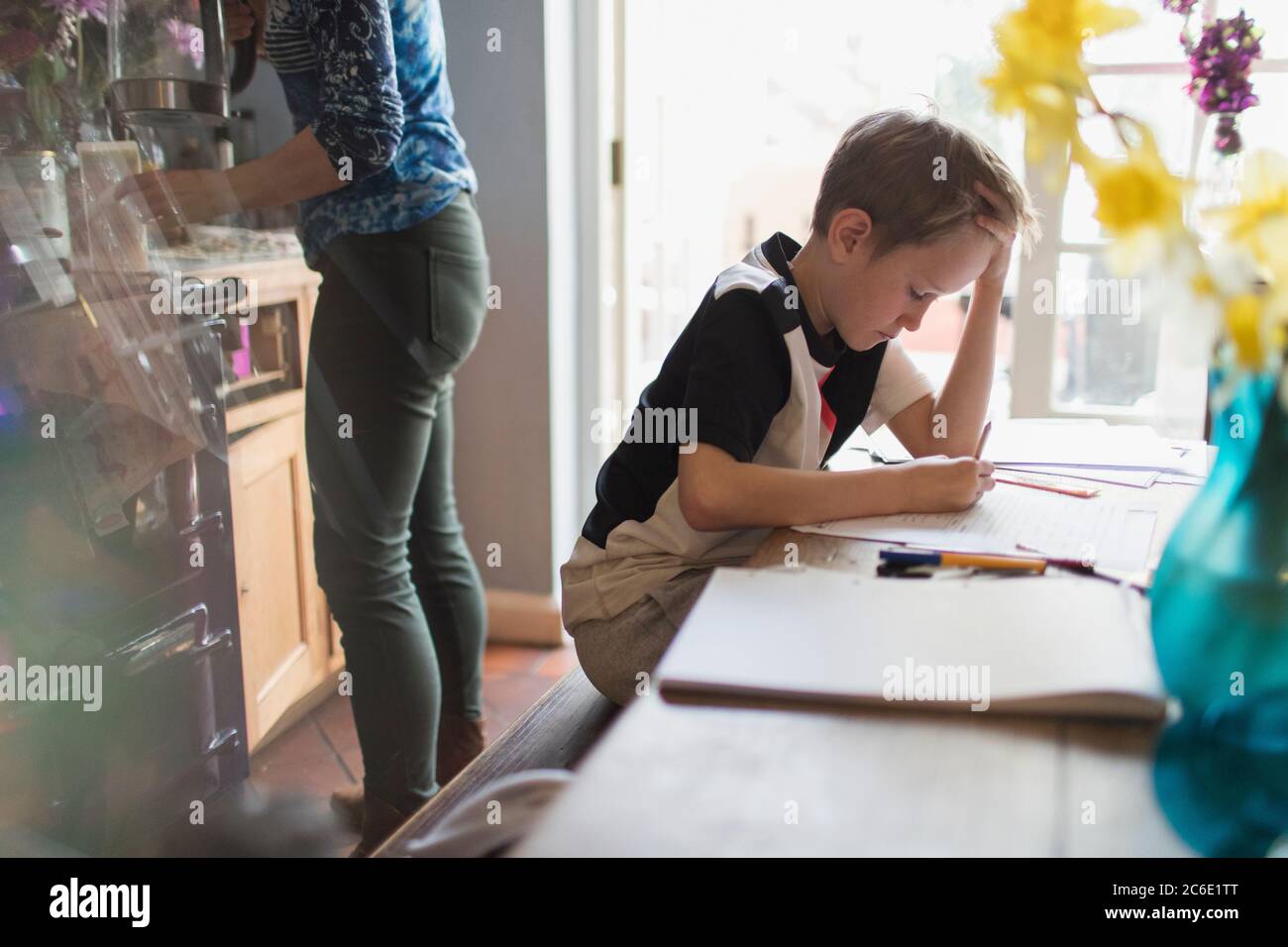 Focused boy homeschooling at kitchen table Stock Photo