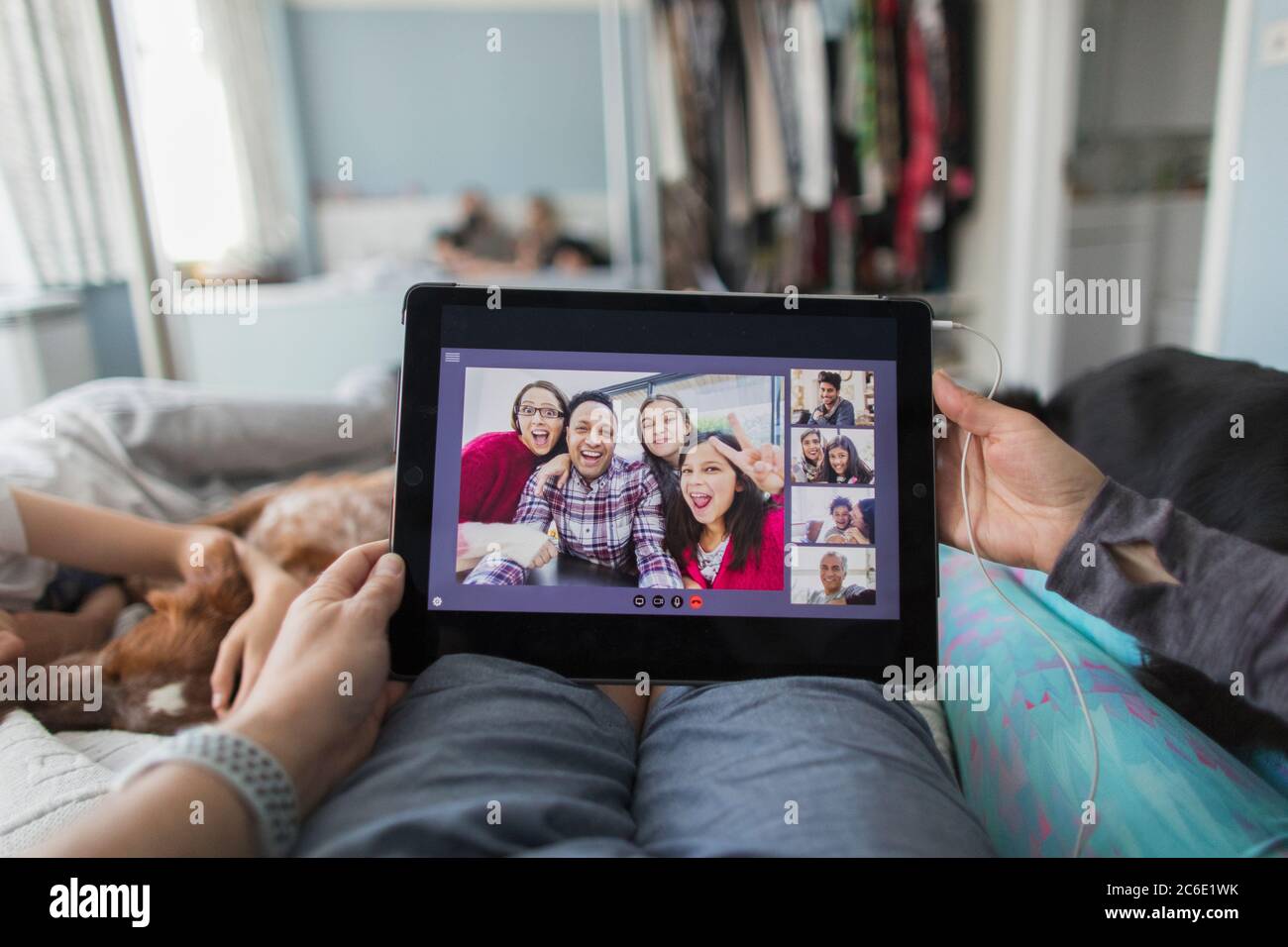 POV woman with digital tablet video chatting with friends on bed Stock Photo