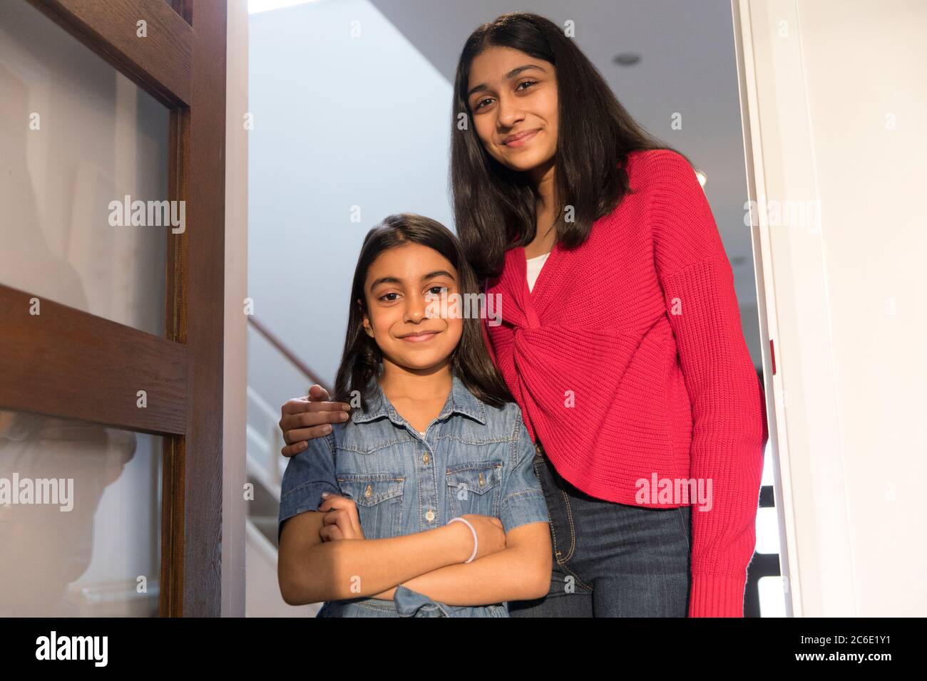 Portrait happy sisters hugging in doorway Stock Photo